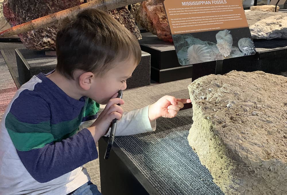 child looking at a large stone