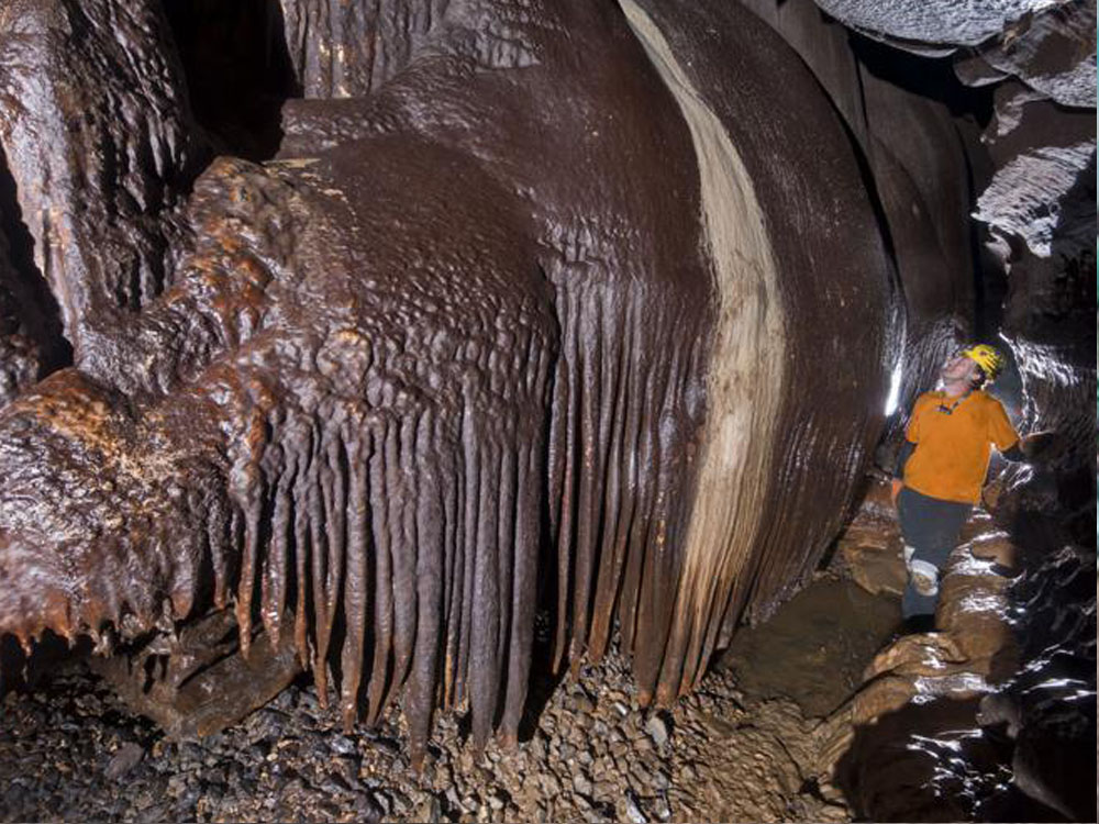 Tourist exploring cave stalactite feature with